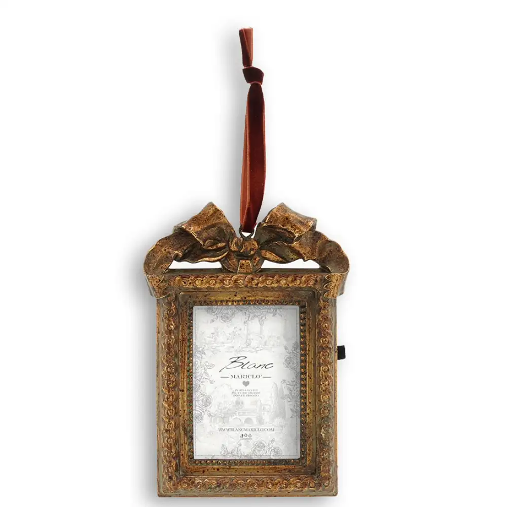Portafoto rettangolare Blanc Mariclo Vivienne in resina dorata antichizzata, con fiocco decorativo e nastro bordeaux.
