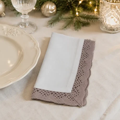 Serviette de table Blanc Mariclò beige clair avec large bord en dentelle ajourée et profil festonné.
